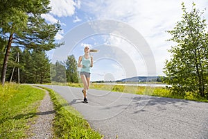 Young woman runs fast on a road in the forest