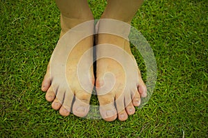 Young woman`s barefoot walking on the fresh, green grass in sunny summer in the morning. Restful moment. Healthy lifestyle. Brigh