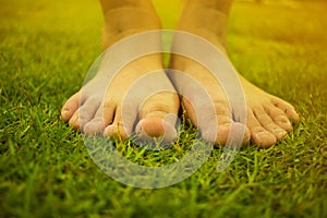 Young woman`s barefoot walking on the fresh, green grass in sunny summer in the morning. Restful moment. Healthy lifestyle. Brigh