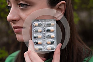 Young woman's face with pills, drinking vitamins for health, chlorophyll tablets, girl jogging in the morning