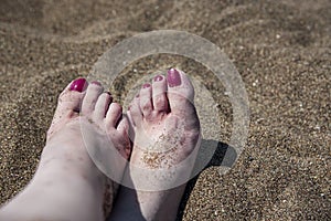 A young woman`s feet on a hot sand, close up