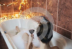 Giovane mano possesso vino bicchiere vasca da bagno potabile vino rosso un sdraiarsi vasca da bagno bolla schiuma, 