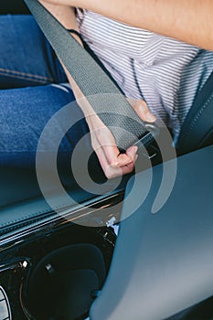 Young woman`s hand putting on seatbelt