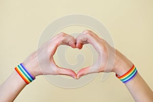 Young woman`s hands with LGBT colorful rainbow flag wristbands shaped as heart