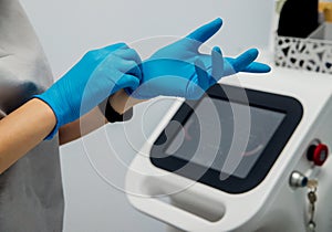 A young woman`s hands are put on medical gloves, preparing for the laser hair removal procedure