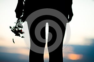 Young woman`s legs and bouquet of meadow flowers