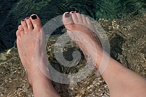 Young woman's manicured feet in water