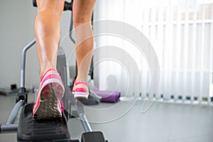 Young woman`s muscular legs on stepper treadmill