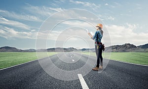 Young woman in safety helmet standing on road