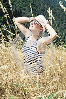 Young woman in sailor outfit smiles to the sun with hands behind