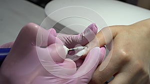 Young woman in the salon does a manicure. A manicurist uses a drill machine to remove nails. Closeup.