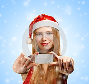 Young woman in santa claus hat with christmas greeting card