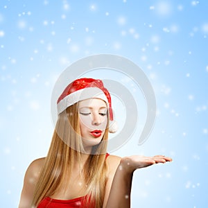 Young woman in santa hat blows on open hand