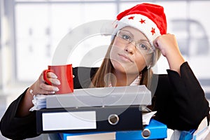 Young woman in santa hat exhausted in office