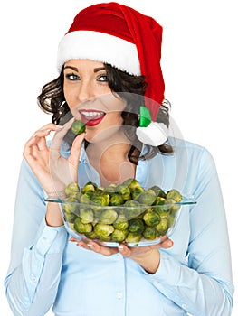 Young Woman in Santa Hat Holding a Bowl of Brussel Sprouts