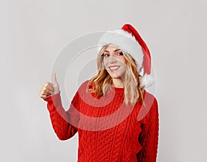Young woman in santa hat smiling and doing okey sign