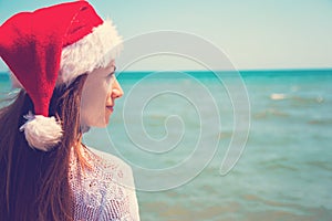 Young woman in santa hat on tropical beach. Christmas vacation. Christmas beach vacation travel woman wearing Santa hat and bikini