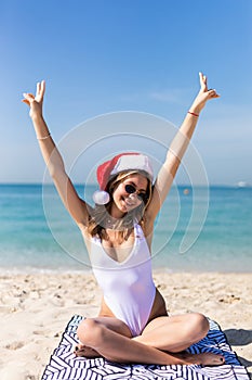 Young woman in santa hat on tropical beach. Christmas vacation. Christmas beach vacation travel woman wearing Santa hat and bikini