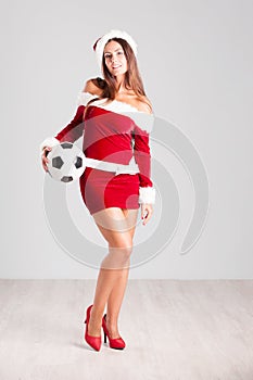 Woman in Santa outfit holding a football`s ball