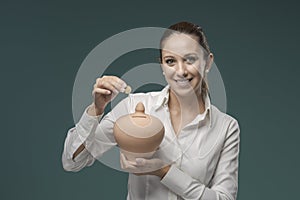 Young woman saving money in a coin bank