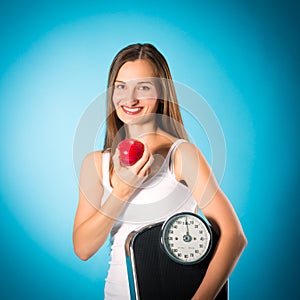 Young woman with scale under her arm and apple