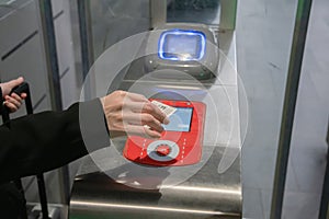 young woman scanning an e-ticket at the terminal at the subway gate