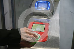 young woman scanning an e-ticket at the terminal at the subway gate