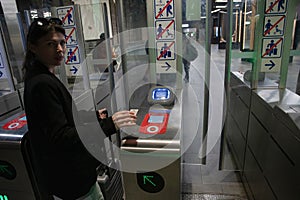 young woman scanning an e-ticket at the terminal at the subway gate