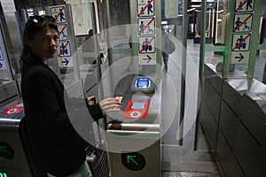 young woman scanning an e-ticket at the terminal at the subway gate photo