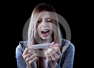 Young woman scared and shocked holding pregnancy test positive result looking unhappy