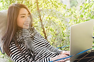 Young woman with scarf use laptop lying in hammock, freelance li