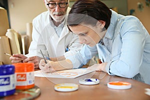 Young woman at school with professor studying painting