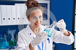 Young woman scientist measuring liquid working at laboratory