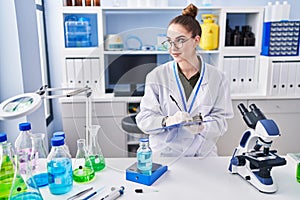 Young woman scientist measuring liquid writing on document at laboratory