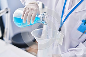 Young woman scientist pouring liquid on test tube at laboratory