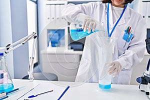 Young woman scientist pouring liquid on test tube at laboratory