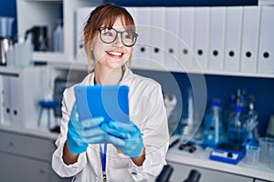 Young woman scientist smiling confident using touchpad at laboratory
