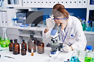Young woman scientist using microscope working at laboratory