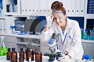 Young woman scientist using microscope working at laboratory