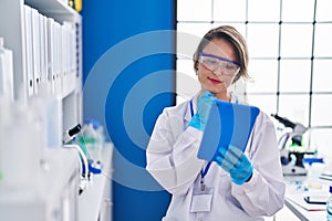 Young woman scientist using touchpad with doubt expression at laboratory