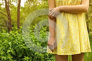 Young woman scratching hand outdoors. Seasonal allergy