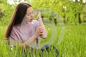 Young woman scratching hand outdoors. Seasonal allergy