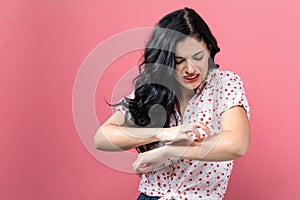 Young woman scratching her itchy arm.