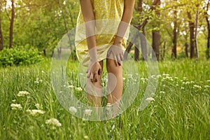 Young woman scratching leg outdoors. Seasonal allergy