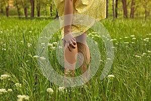Young woman scratching leg outdoors. Seasonal allergy