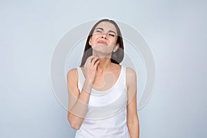 Young woman scratching neck on light background photo