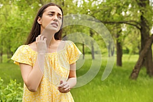 Young woman scratching neck outdoors. Seasonal allergy