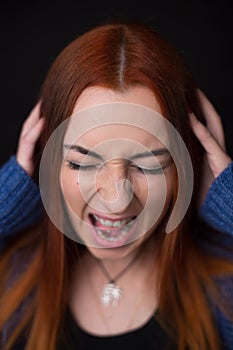 Young woman screaming at black background.