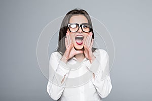 Young woman screaming loudly isolated on gray background