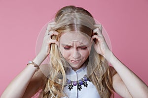 young woman screaming from pain and holding her head with selective focus